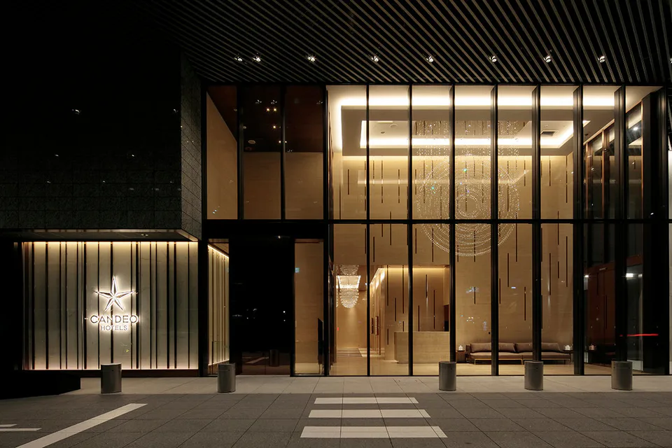 Entrée vitrée illuminée du CANDEO HOTELS Osaka The Tower de nuit