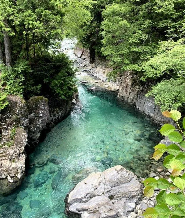 Inugaeri-no-fuchi pool in Atera Valley with clear turquoise water between forested rock walls