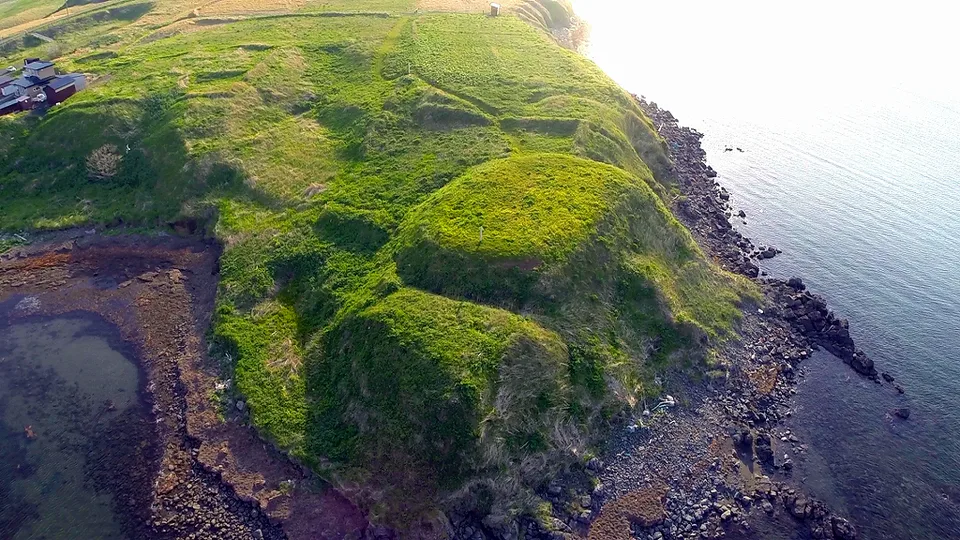 Vue aérienne du site de Onnemoto Chashi, permettant d’identifier les remblais, fossés et deux surfaces planes sur la péninsule.