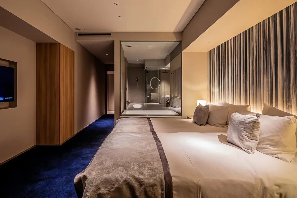 MUWA Niseko contemporary guest room with bed and glass-walled bath