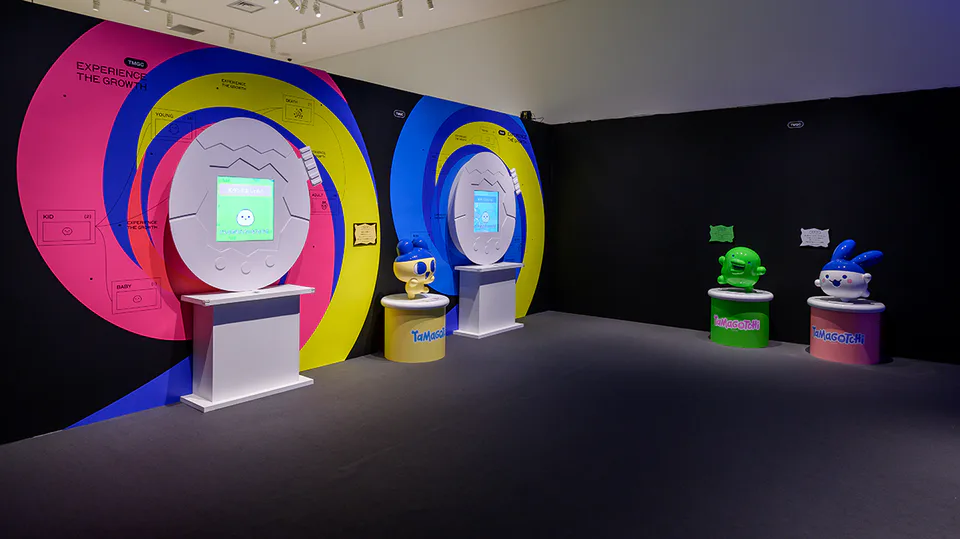 ภาพถ่ายอุปกรณ์แสดงผลและสิ่งของในงานแสดง Tamagotchi อย่างเป็นทางการในสีสันสดใส