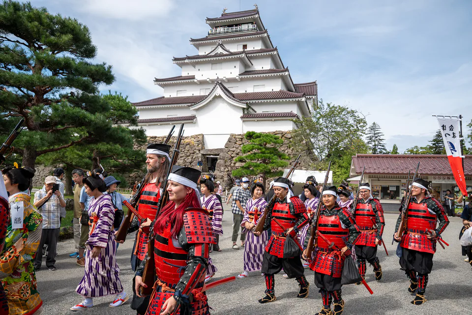 Tsuruga Castle in Aizuwakamatsu with historical-costume participants in front of the reconstructed red-tiled keep