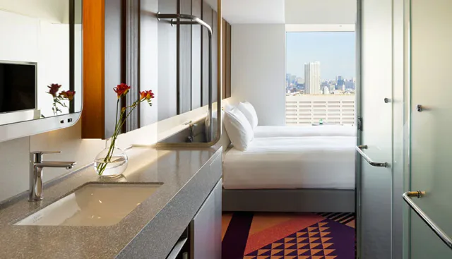HOTEL GROOVE SHINJUKU guest room with bed and Shinjuku skyline