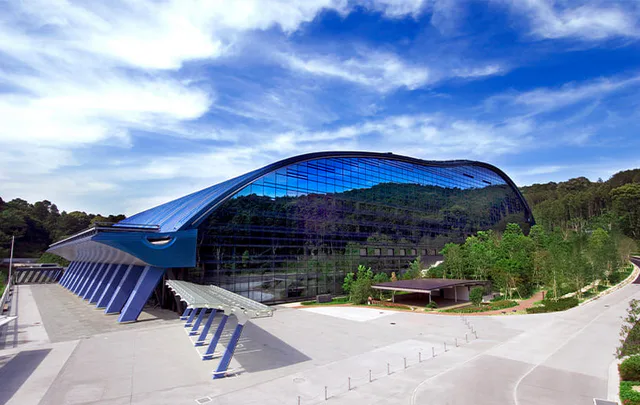 Kyushu National Museum exterior in Dazaifu, with its curved blue-glass facade reflecting the wooded hillside
