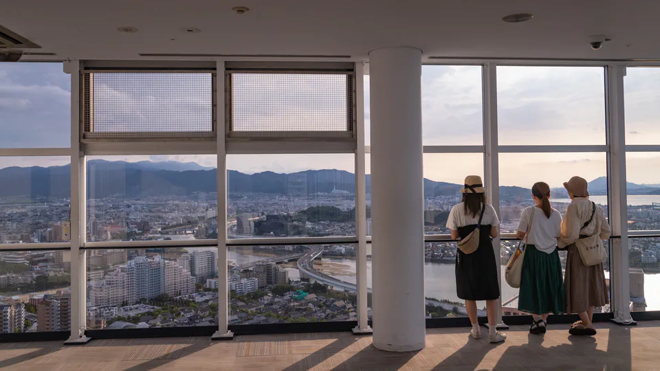 Visitors looking across Fukuoka from the observation deck during the late-afternoon light