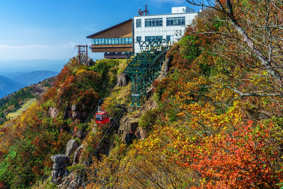 Gozaisho Ropeway passing through layered red, yellow and green autumn foliage on Mount Gozaisho