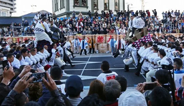 Sur le site du festival d'automne de Matsuyama devant la station Dōgo Onsen, le mikoshi principal fait face à une foule dense, séparés par une zone de sécurité.