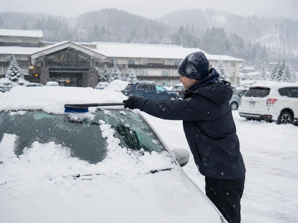 Clearing snow from a parked rental car in Hokkaido winter