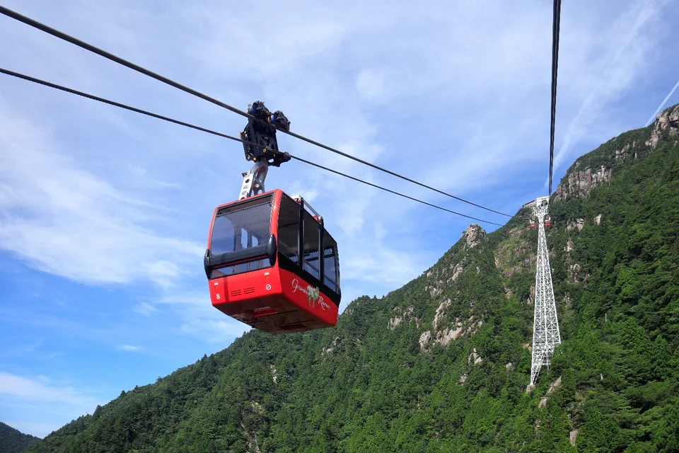 Red Gozaisho Ropeway gondola crossing the green slopes of Mount Gozaisho in Mie