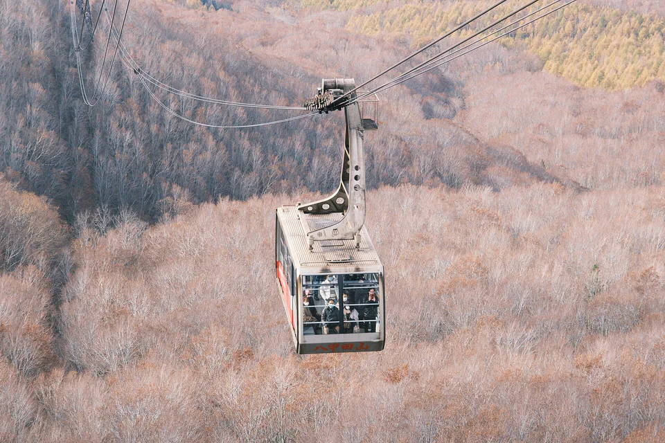 핫코다 로프웨이가 가을 숲 위를 지나며 성수기 대기시간이 필요한 모습