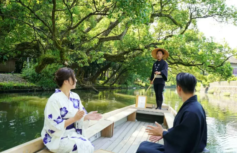 柳川伯舟觀光忍者船夫遊船實景,木船在低橋與水鄉河道之間前進